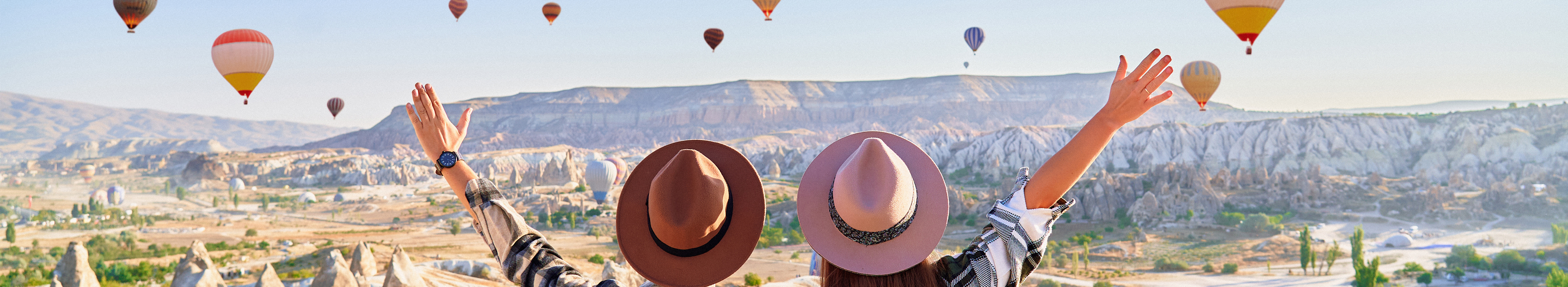 Paar in Kappadokien mit fliegenden Heißluftballons bei Sonnenaufgang