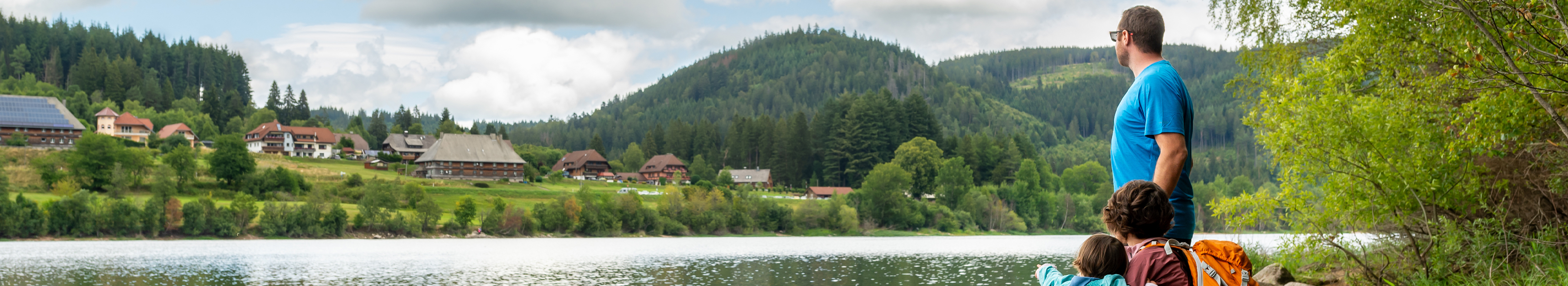 Familie blickt von der anderen Seite des Sees auf das Dorf Schluchsee im Schwarzwald, Deutschland