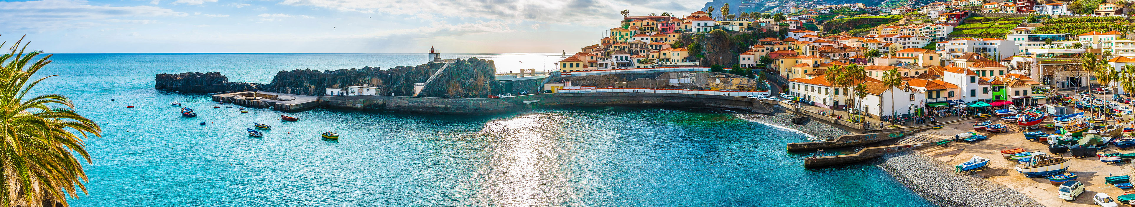 Urlaub Madeira.Bunte Häuser am Meer mit Bucht und kleinem Anlegerhafen.