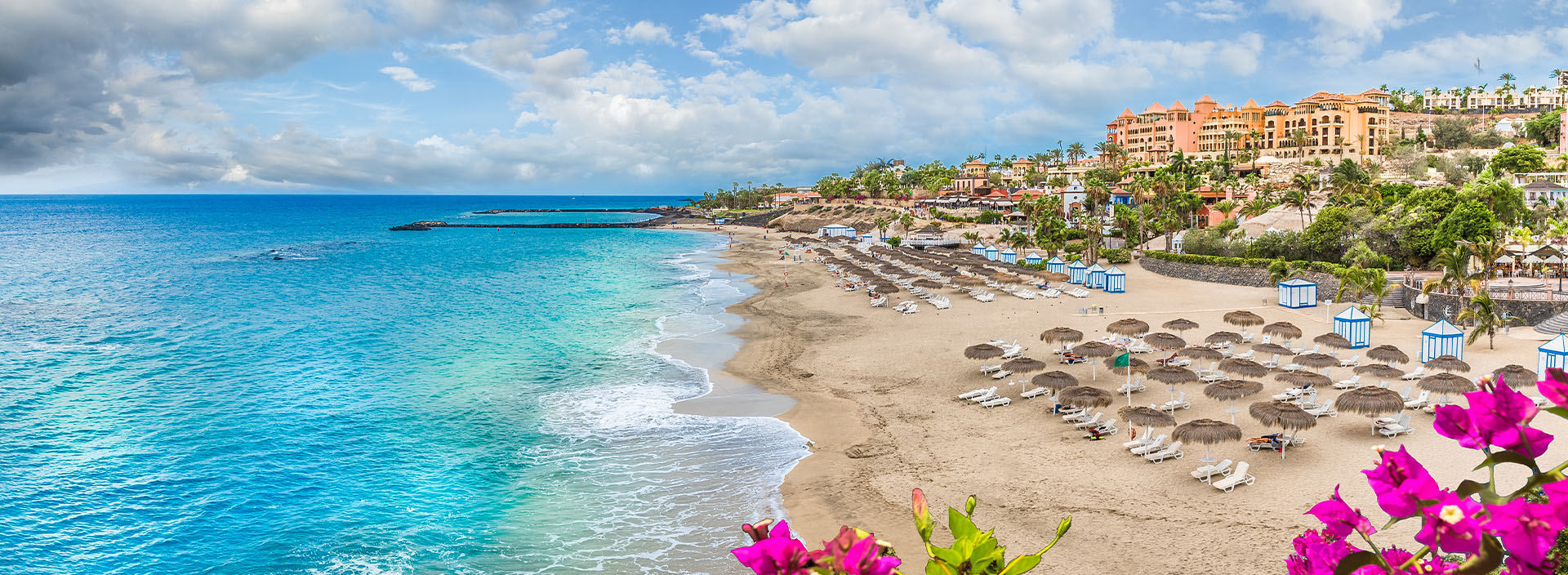 Ein Küstenabschnitt in Spanien mit Sandstrand und Sonnenliegen.