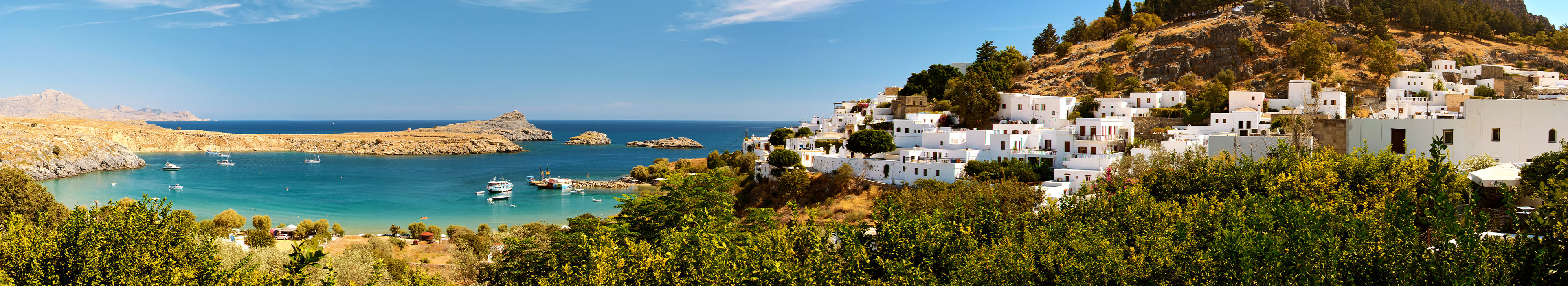 Urlaub Rhodos. Küstenabschnitt mit weißen Häusern auf einem Hügel unter blauem Himmel.