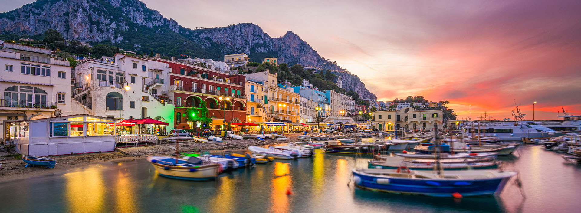 Promenade am Strand in Italien mit Hotels und Booten.