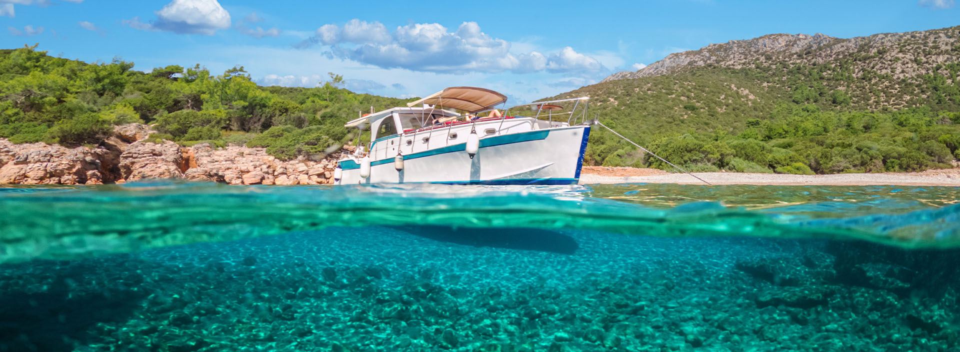 Marineyacht im Meer und halbe Unterwasseransicht des Meeresbodens in Bodrum, Türkei.
