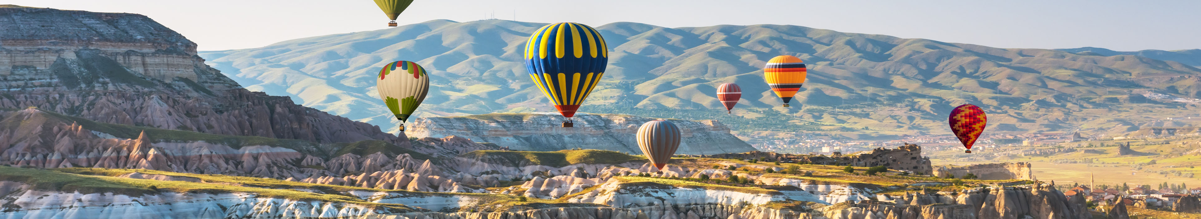 Heißluftballons fliegen über die Landschaft in Kappadokien, Türkei.