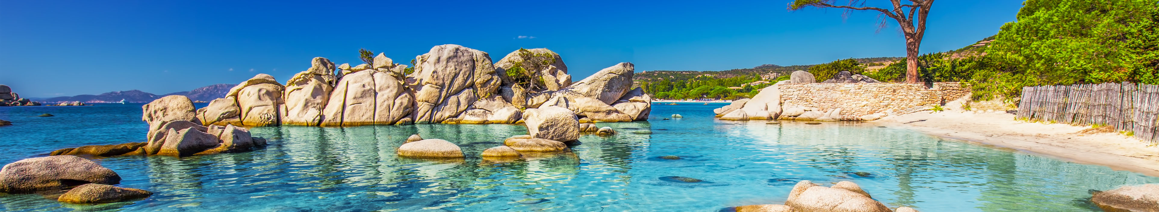 Kiefern Bäume und kleine Felsen im Meer am Palombaggia Strand, Korsika.