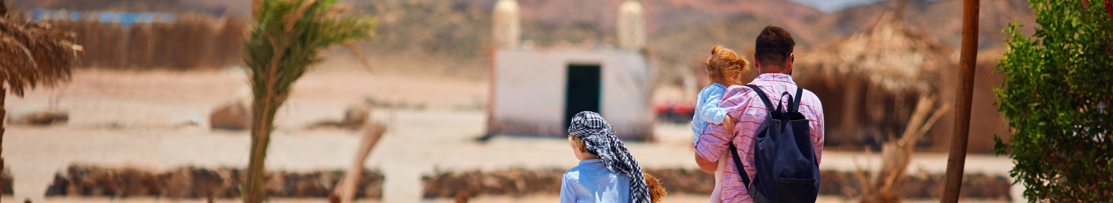 Familie mit Kindern, Touristen, die während einer Safari durch ein Beduinendorf in der Wüste wandern