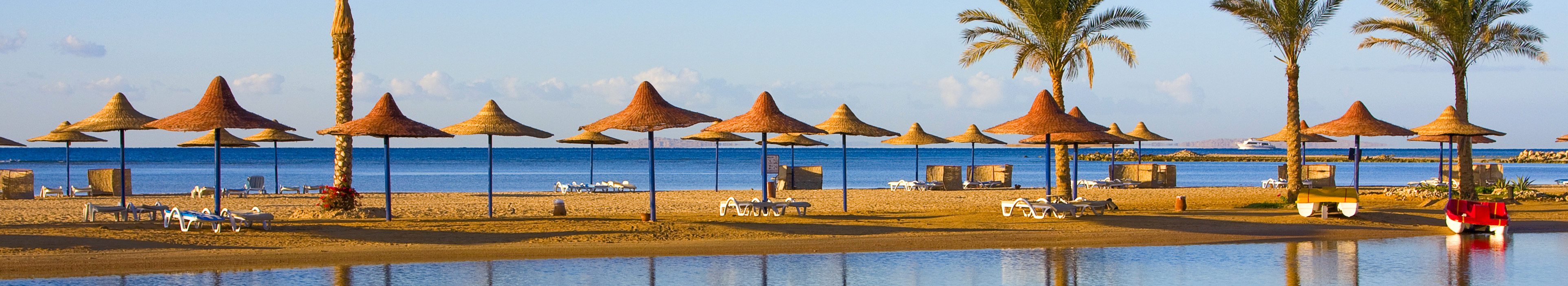 Traumstrand mit Palmen und Sonnenschirmen aus Stroh, in Sharm El-Sheikh, Ägypten.