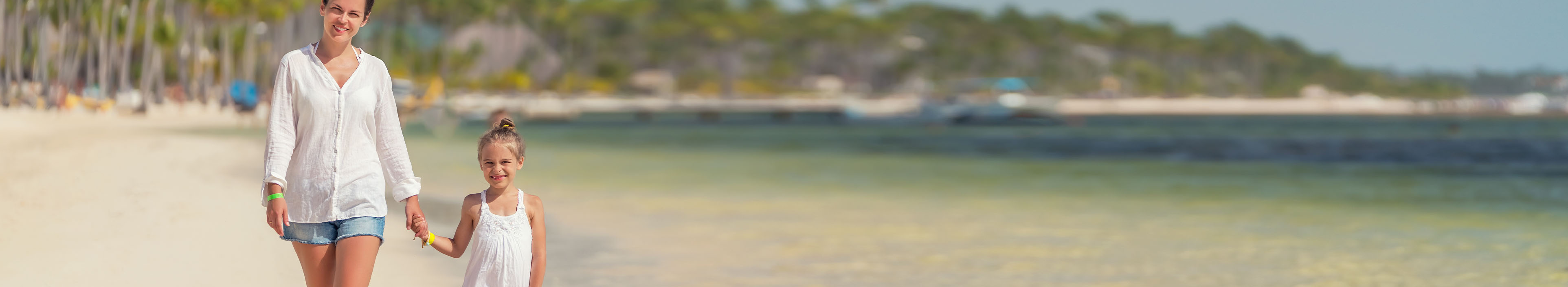 Frau und Tochter spazieren am Sandstrand entlang in der Dominikanischen Republik