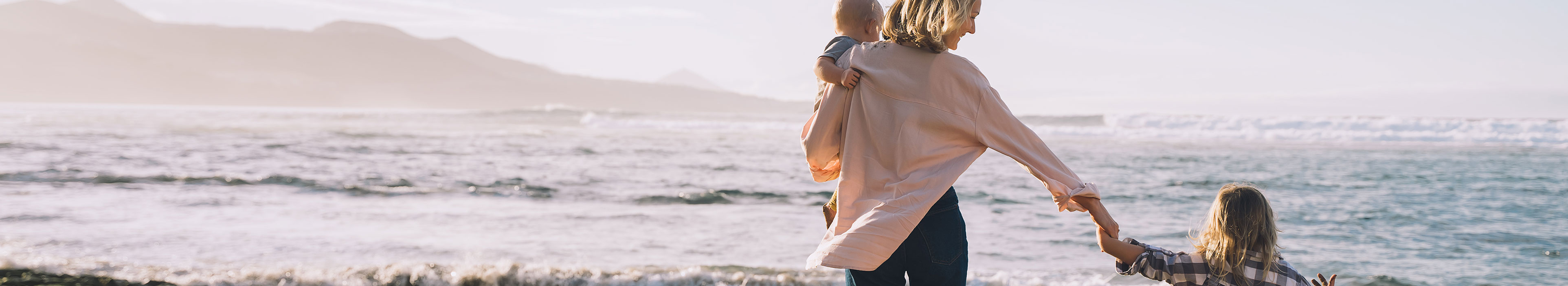 Mutter mit Kindern, die zusammen am Strand spielen und Spaß haben 