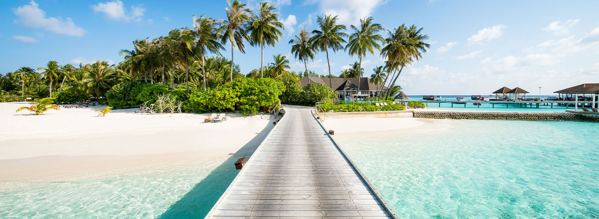 Ein Steg zu einem Hotel auf den Malediven umgeben von einem weißen Sandstrand