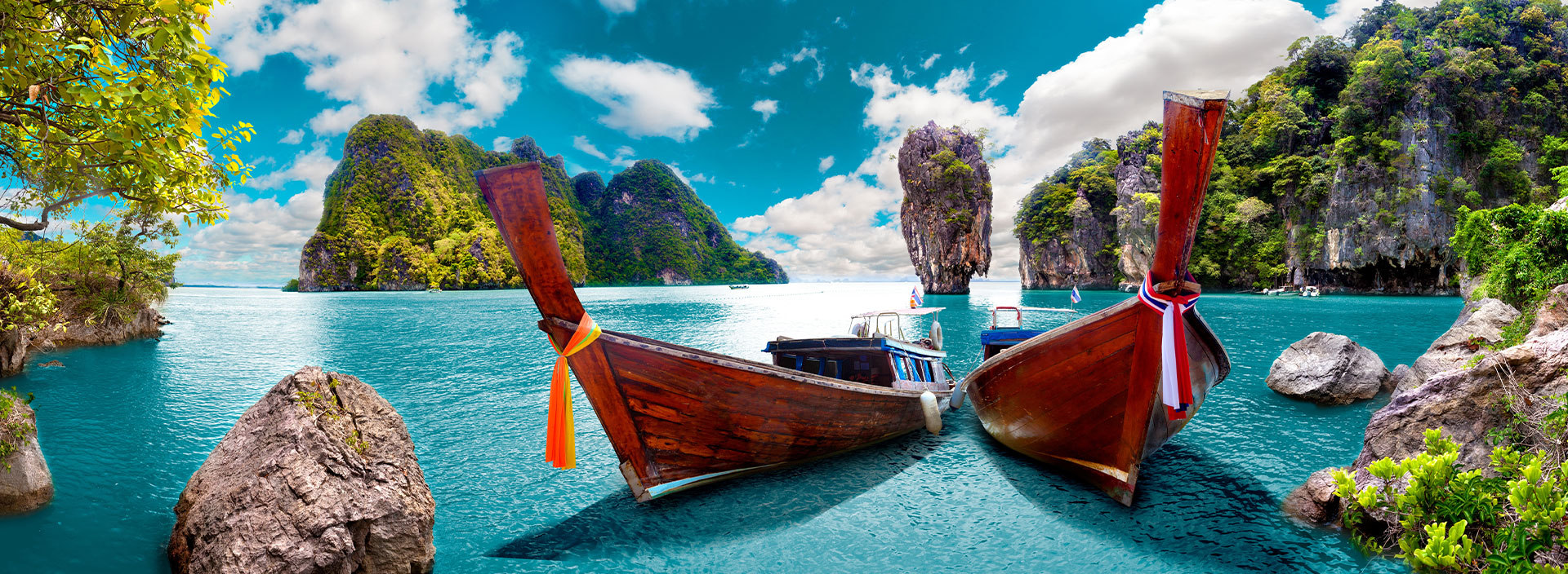 Zwei Boote die im türkisblauem Wasser in einer Bucht vor Thailand liegen